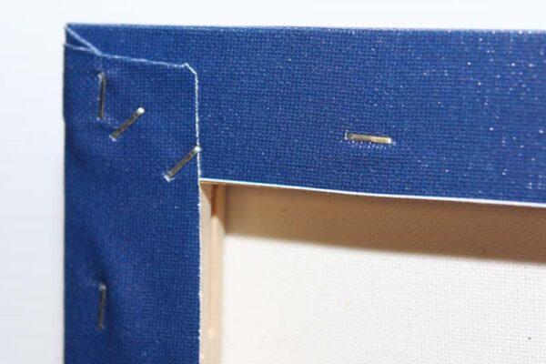 Rear corner of a gallery-wrapped canvas with folded fabric and staples Rear corner of a gallery-wrapped canvas with folded fabric and staples