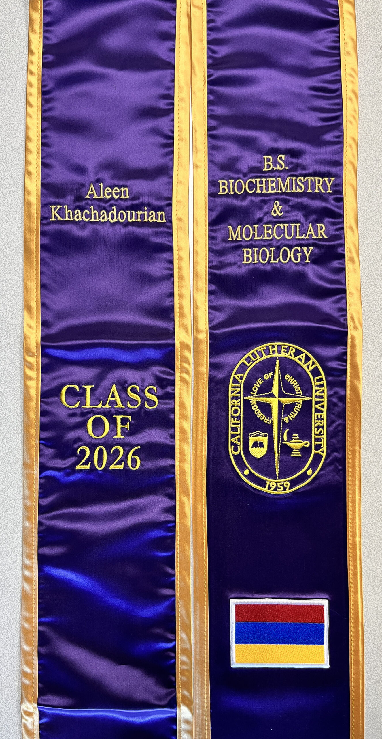 Custom graduation sash for college graduate with embroidered name, school logo, and graduation year