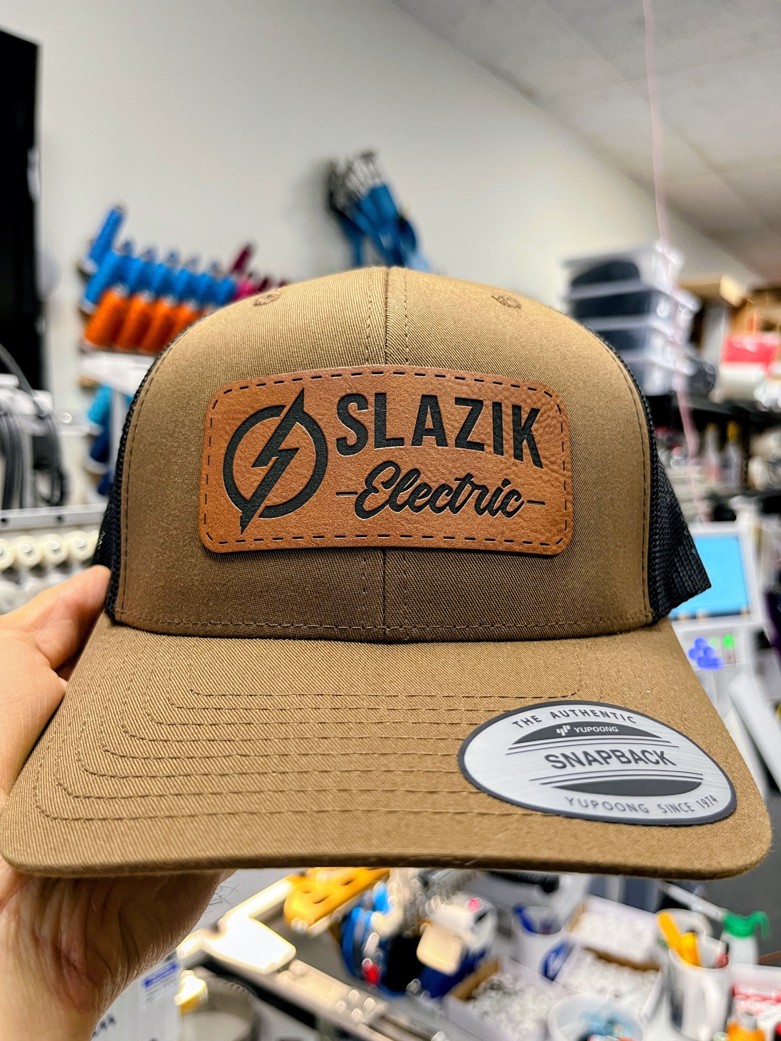 Brown and tan Slazik Electric hat with a rawhide-color logo patch