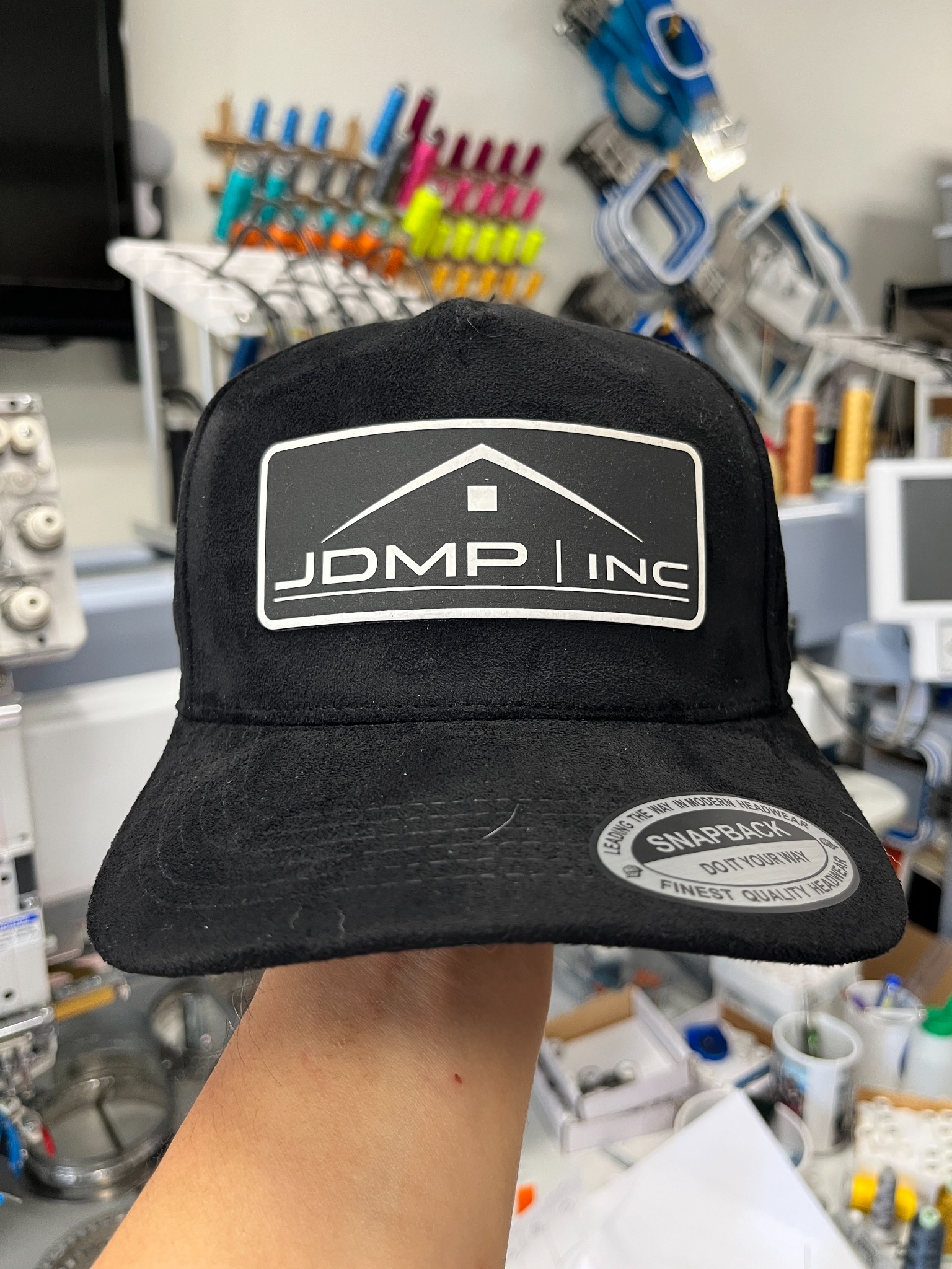 Black suede hat with a rectangular company laser-engraved logo patch
