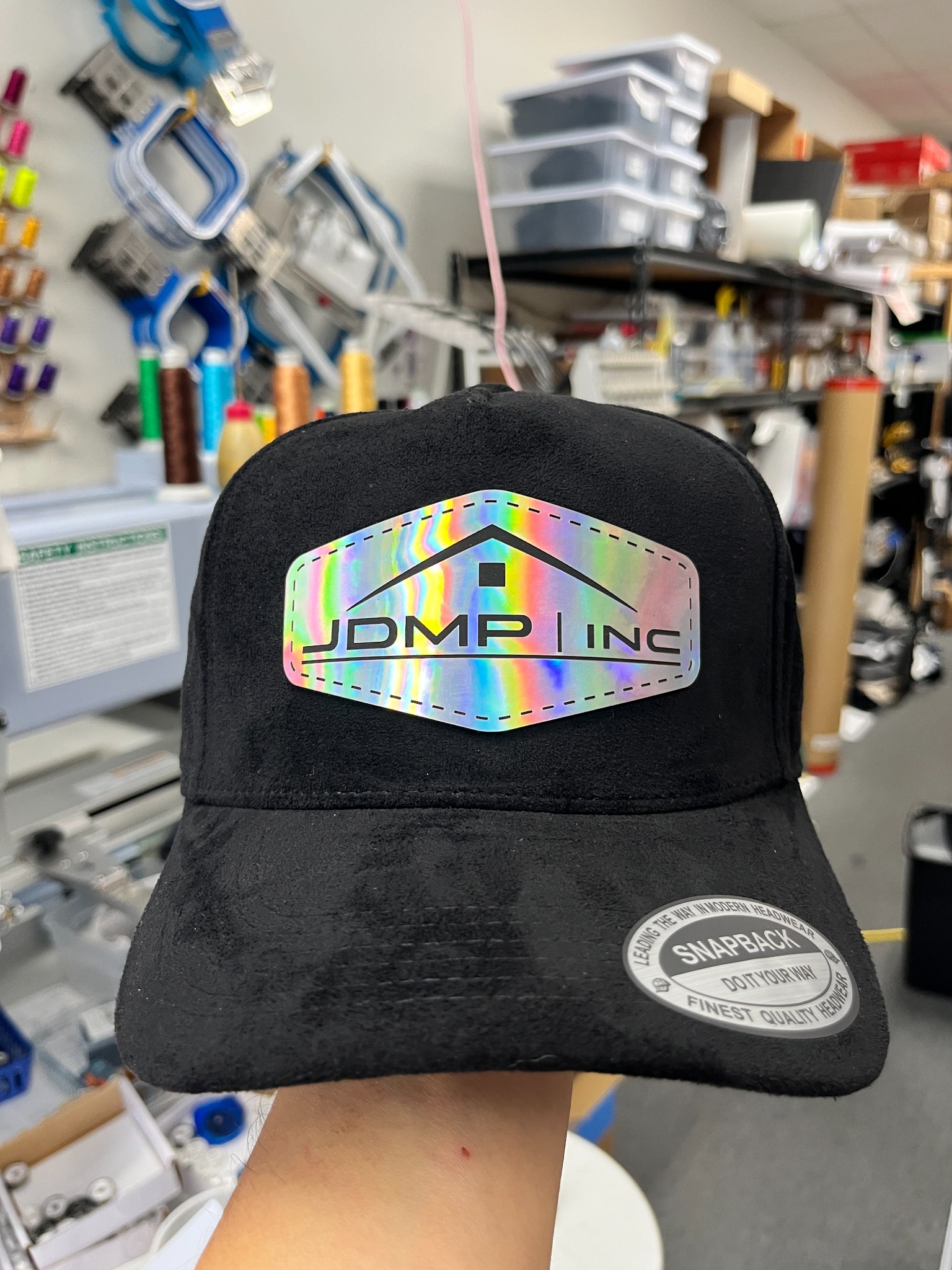 Black suede hat with a bright rainbow holographic company laser-engraved patch