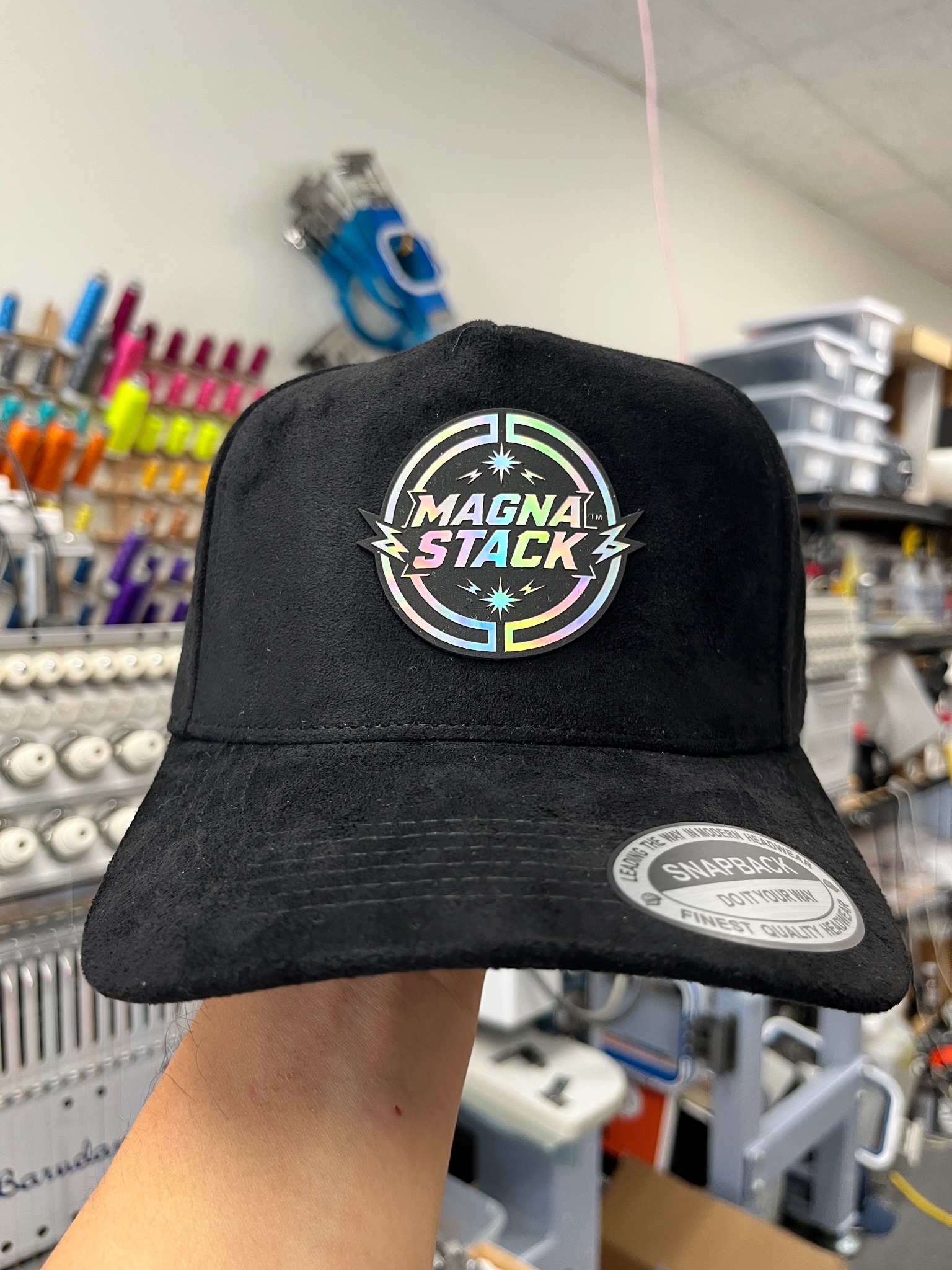Black suede hat with a circular Magna Stack holographic logo patch