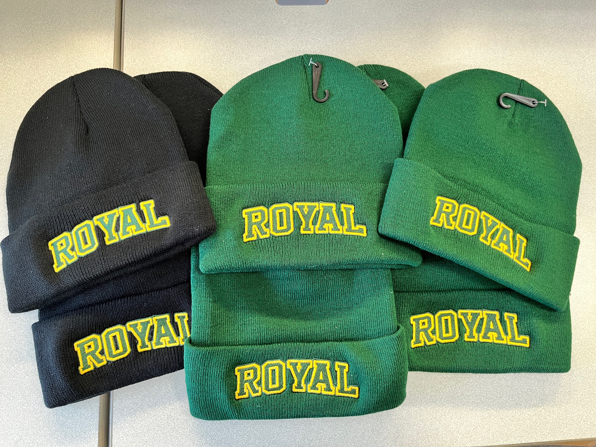 Black and green beanies embroidered with Royal lettering in green and gold