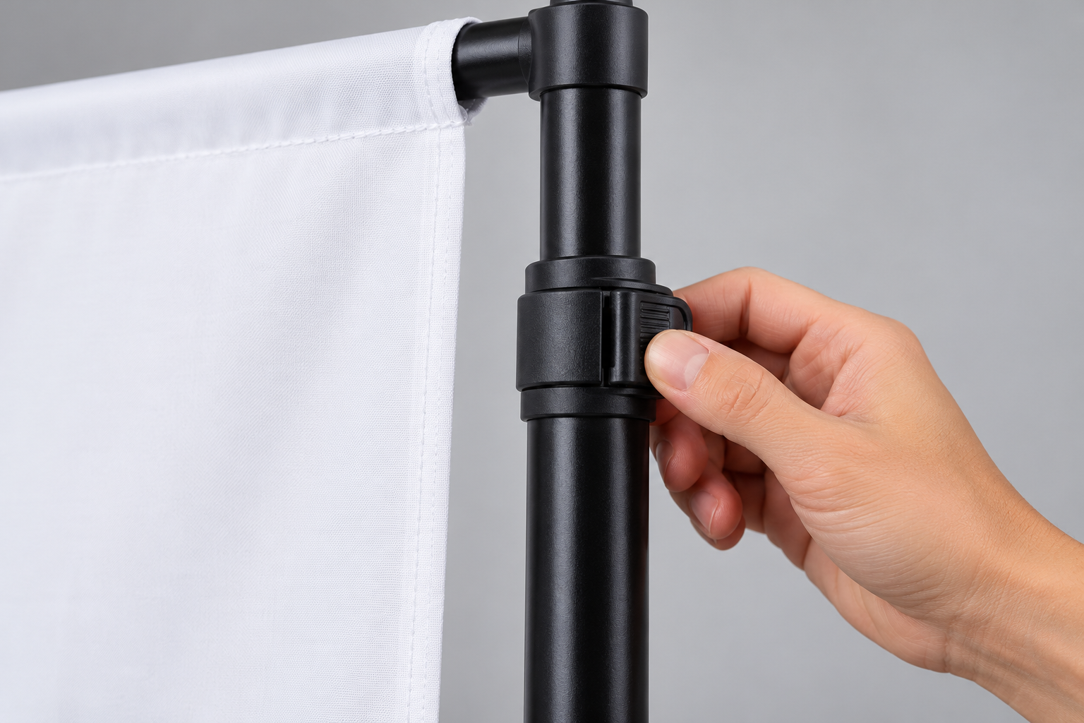 Hand adjusting the height of a black telescoping backdrop stand Hand adjusting the height of a black telescoping backdrop stand
