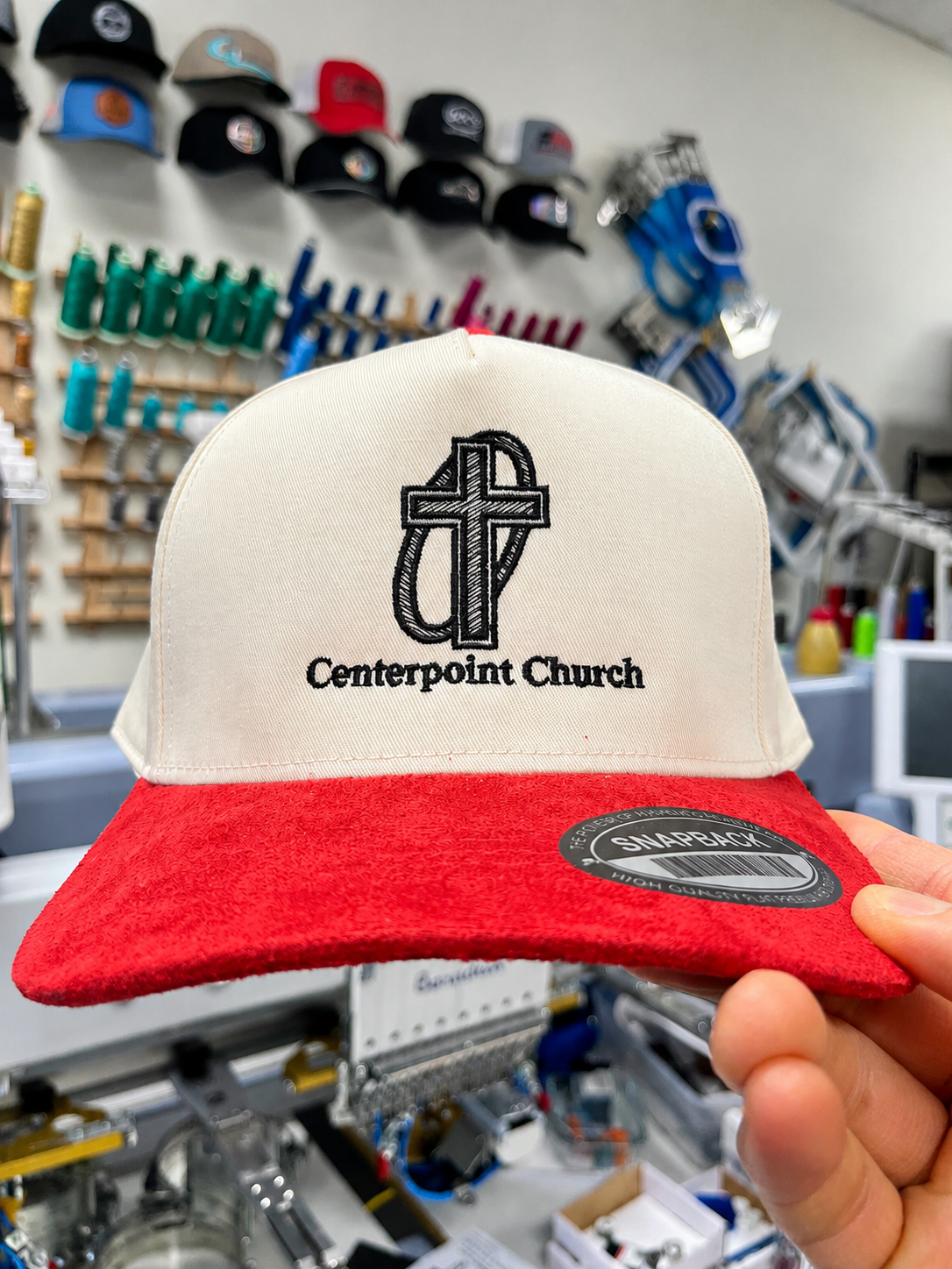 Cream hat with a red bill and black Centerpoint Church logo embroidery