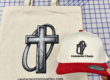 Natural-color Center Point Church tote bag beside a cream and red embroidered hat