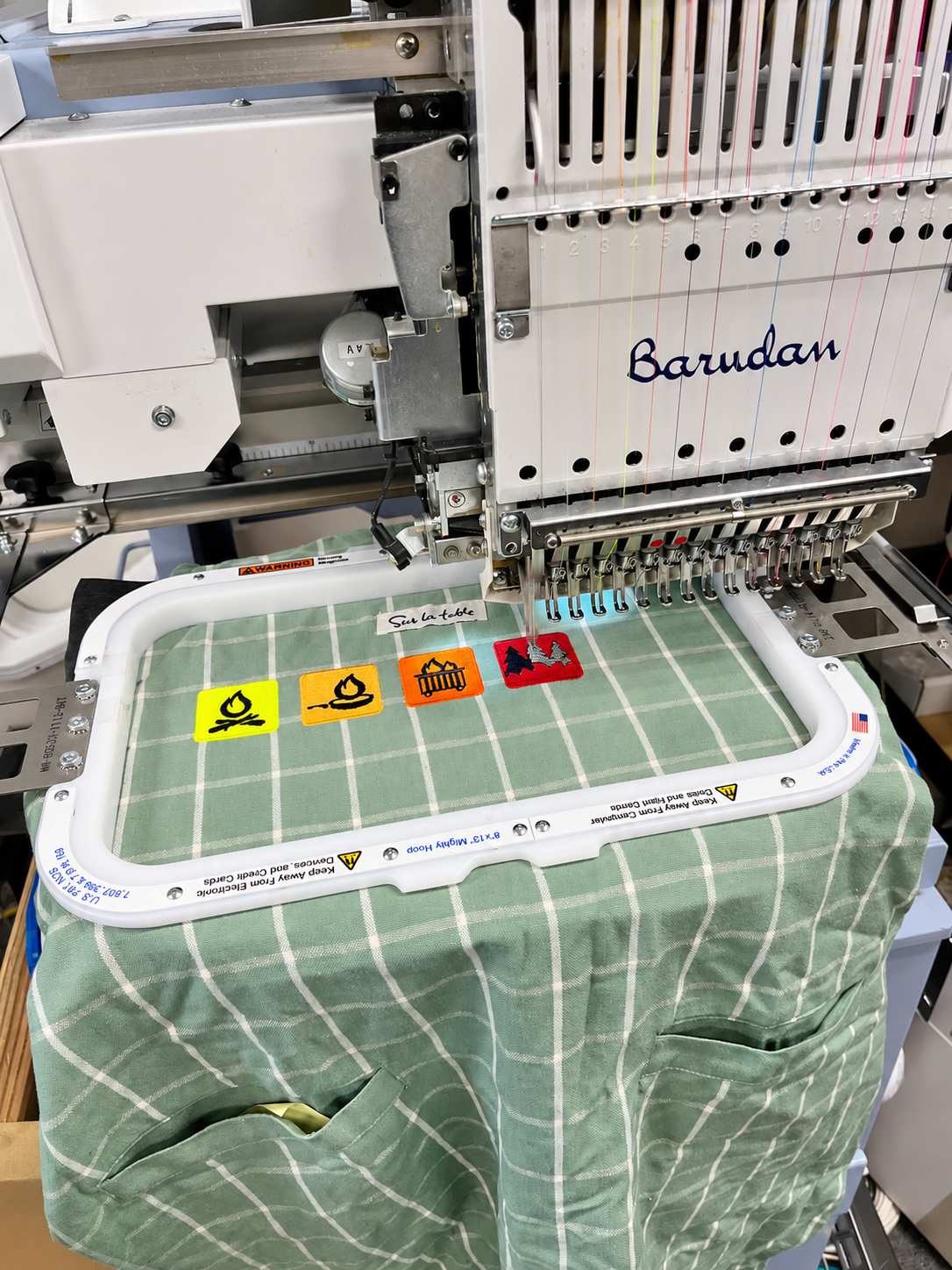 Green checked apron hooped on SpectraColor’s Barudan embroidery machine