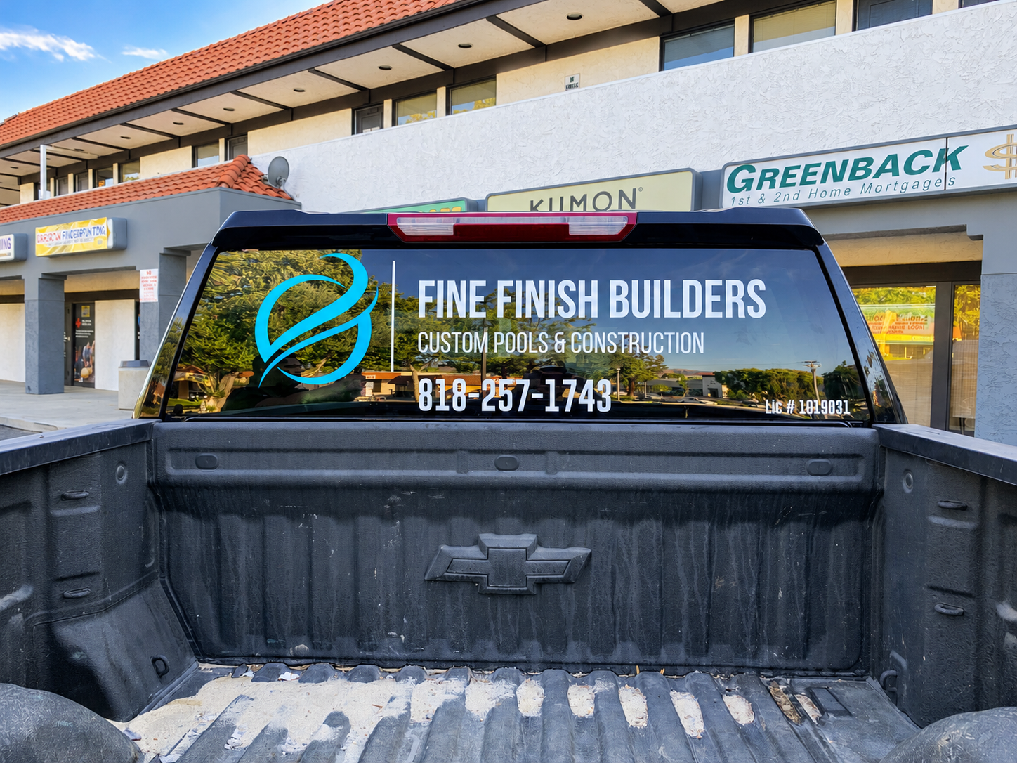 Fine Finish Builders company logo and contact lettering on the rear window of a black pickup.