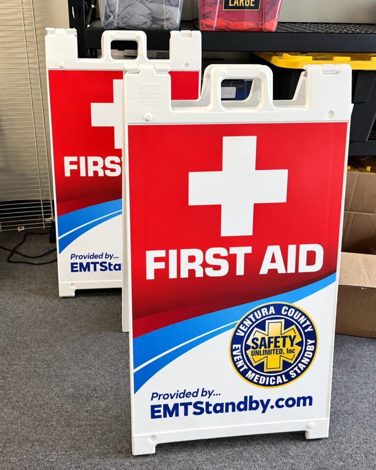 White Standard Signicade A-frame signs with red First Aid graphics and EMTStandby.com branding, printed by SpectraColor in Simi Valley.
