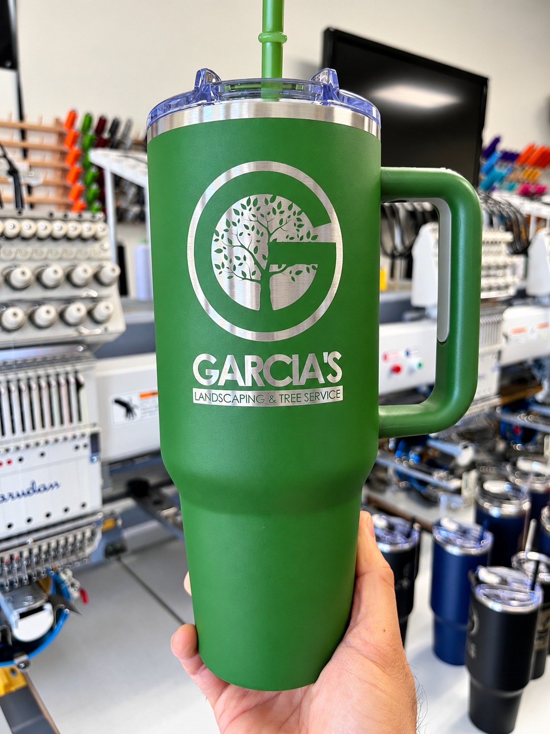 Green handled tumbler laser engraved with Garcia’s Landscaping tree logo and company name.