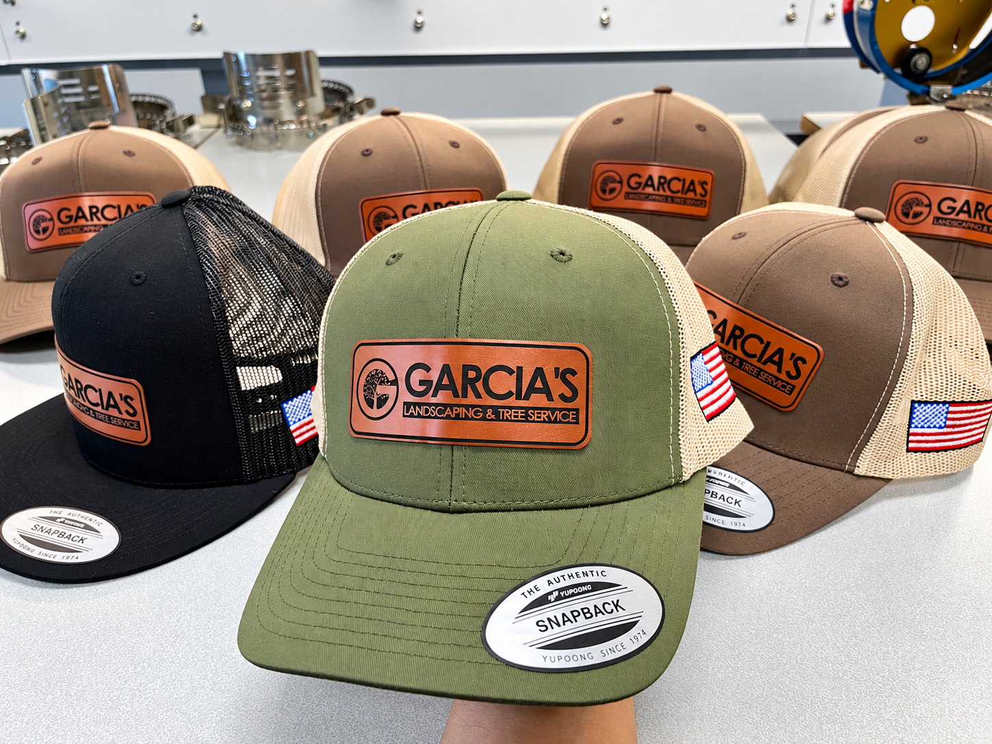 Black, olive and brown Garcia’s Landscaping logo-patch hats with tan mesh backs.