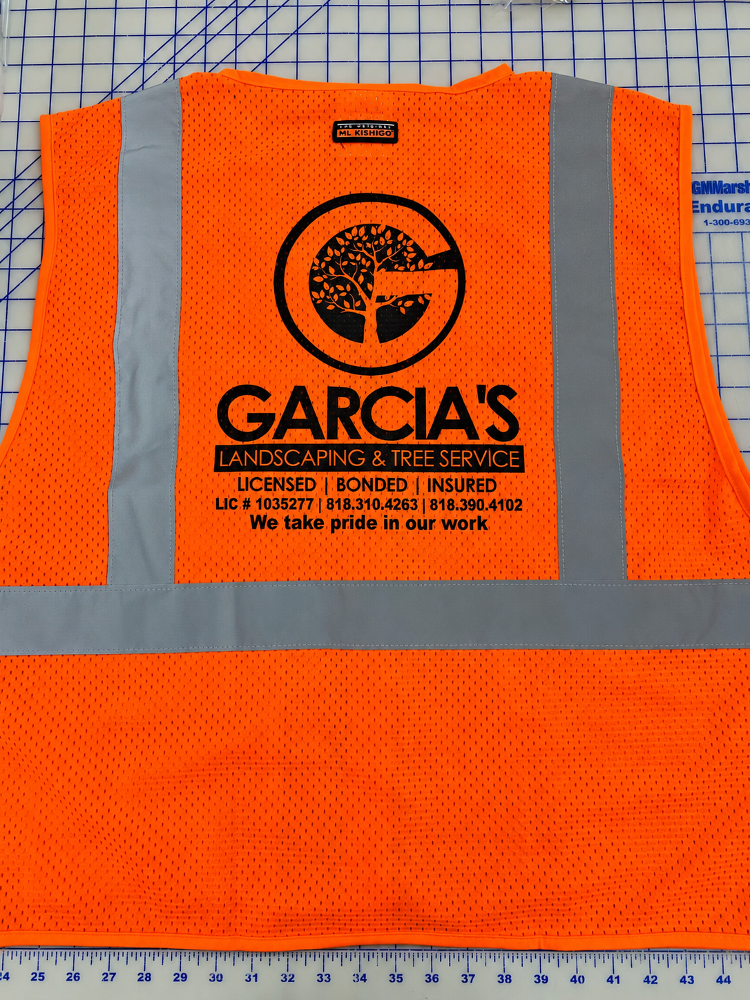 Orange reflective safety vest printed with Garcia’s Landscaping company logo on the back.