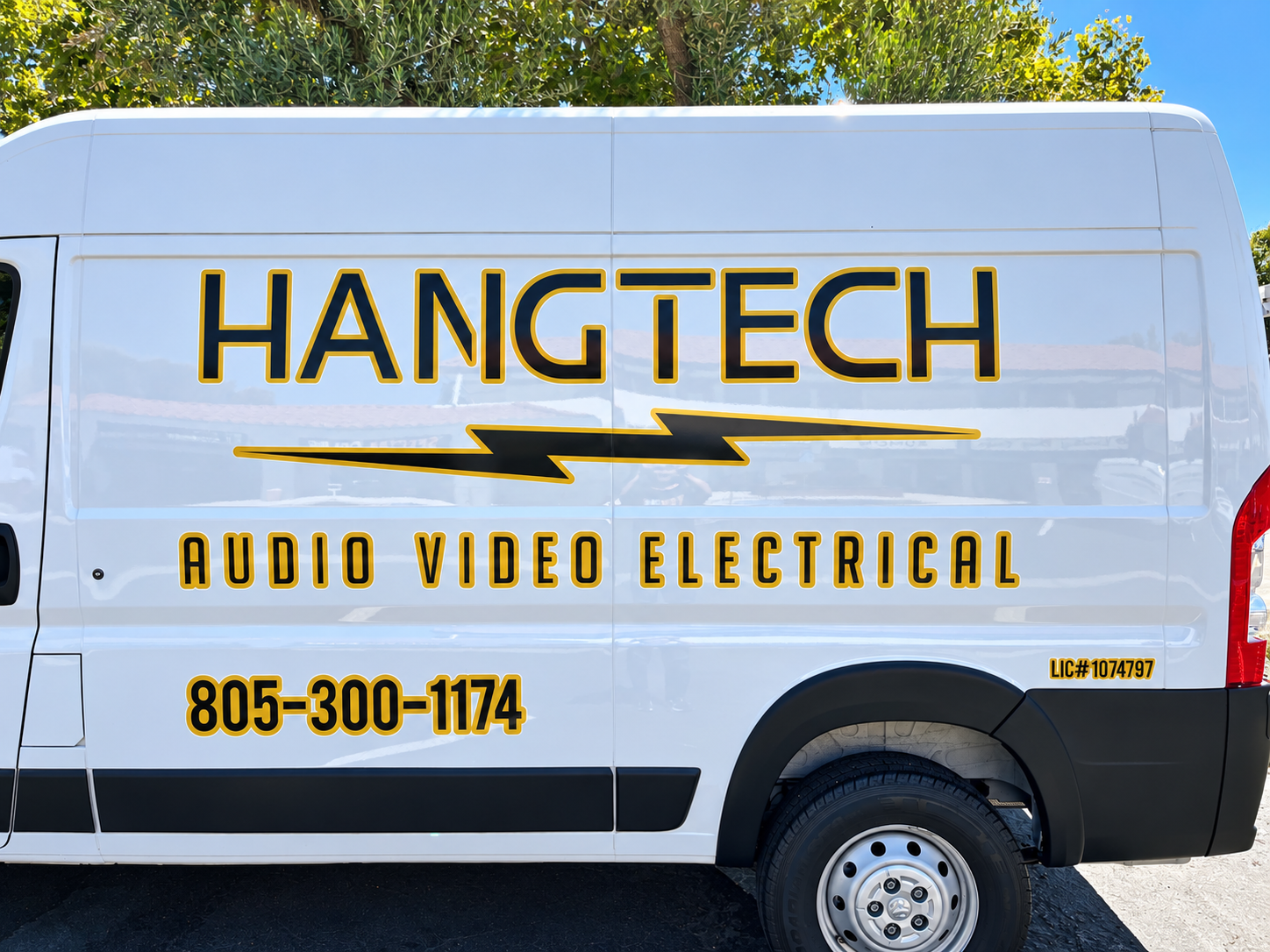 Close-up of Hang Tech black and gold logo and service lettering on a white work van