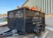 Black JDMP Inc. work trailer with white vinyl logo and company lettering