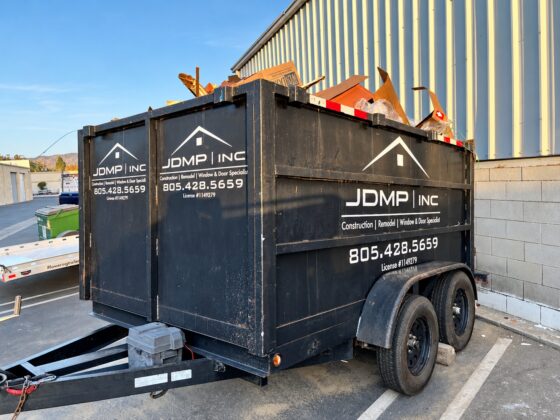 Black JDMP Inc. work trailer with white vinyl logo and company lettering