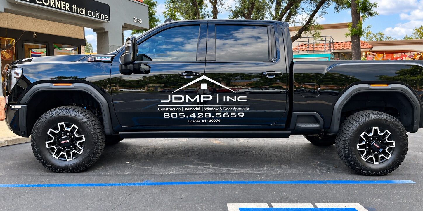Black JDMP Inc. pickup truck with white vinyl company logo and door lettering