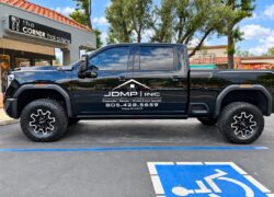 Black JDMP Inc. pickup truck with white vinyl company logo and door lettering