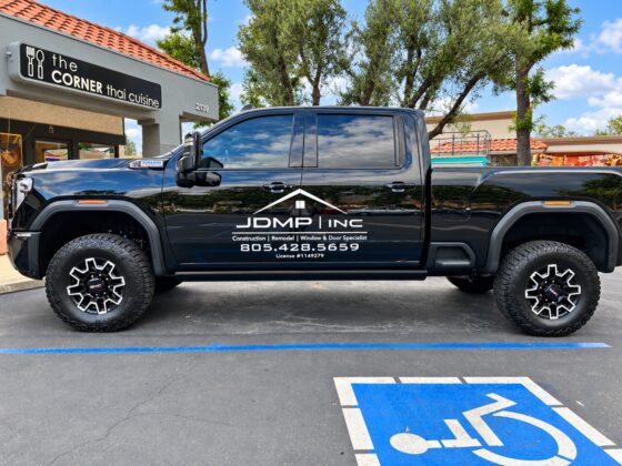 Black JDMP Inc. pickup truck with white vinyl company logo and door lettering