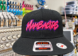 Black Mambacitas hat with pink raised embroidery and a purple outline
