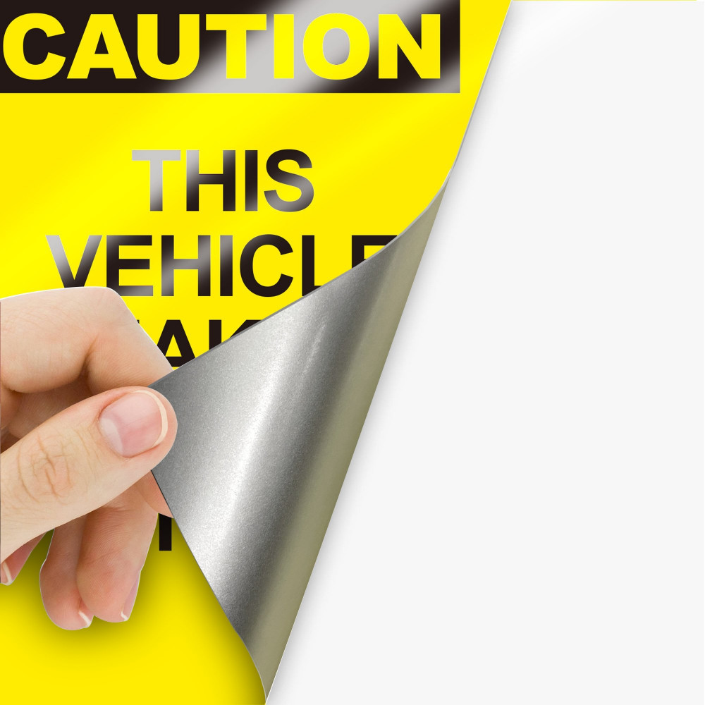 Hand peeling reflective caution sign vinyl to show its silver backing Hand peeling reflective caution sign vinyl to show its silver backing